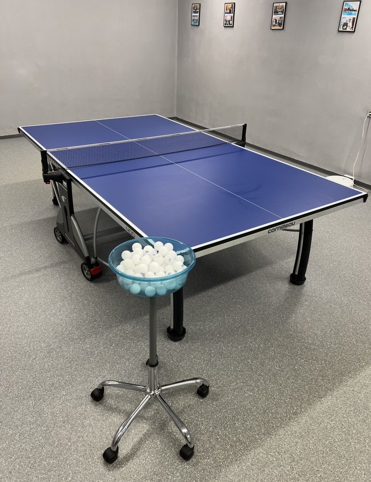 Finished recycled ball stand holding table tennis balls beside a training table